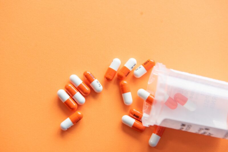 orange and white pills in a prescription vial