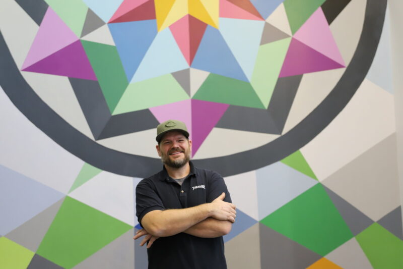 Artist Derrick Toebbe in front of ATLC mural