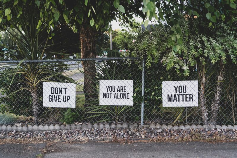 Signs on a fence: Don't give up. You are not alone. You matter