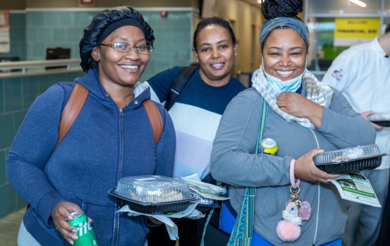 Three smiling students with Thanksgiving lunches