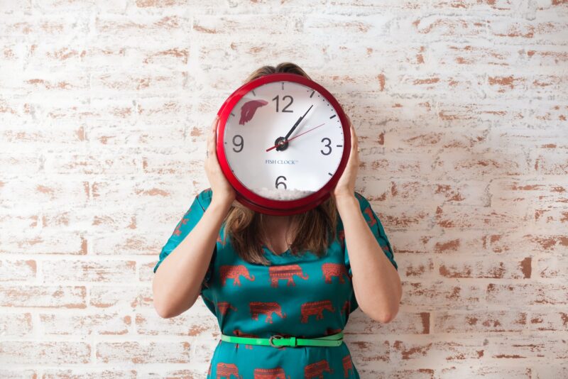 woman covering face with a wall clock