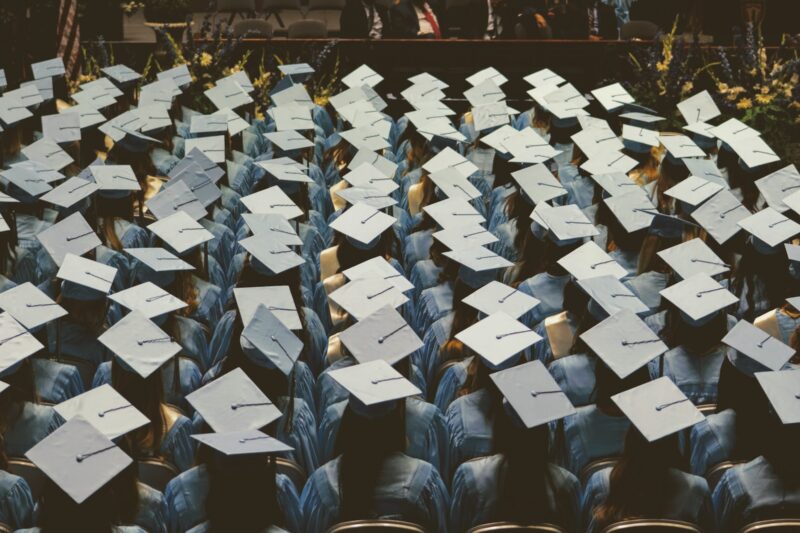 students seated at graduation, seen from above with tops of caps showing