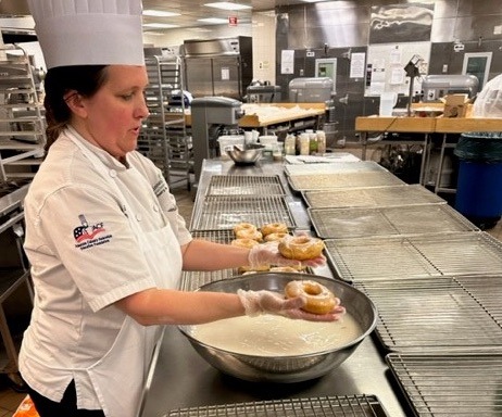 Student glazing donuts