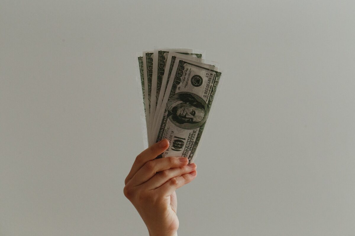 hand holding several US paper money bills