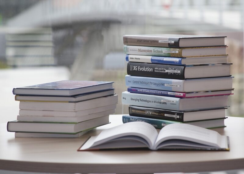 two stacks of books and one open book on a table
