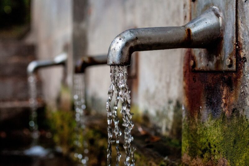 two silver water faucets with water droplets coming from the faucets