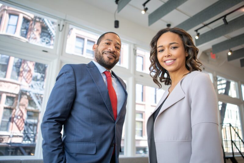 Man in blue business suit with red tie and woman in grey business suit