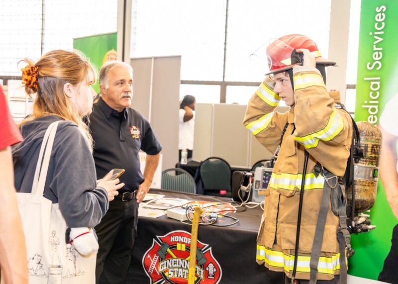 ENGAGE 2023 visitor tries on fire fighting equipment