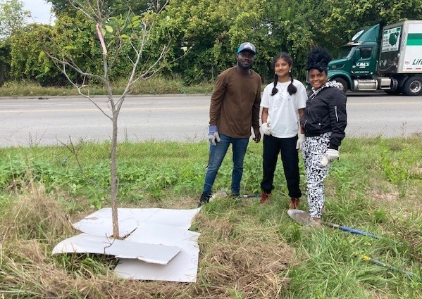 Students pose near the tree they planted