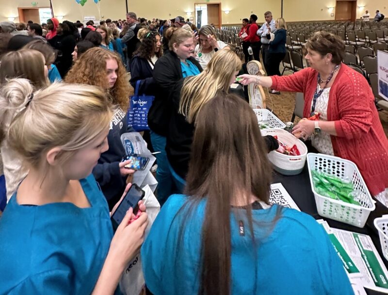 Students in blue scrubs receive information about Cincinnati State Health & Public Safety programs at HealthFORCE event