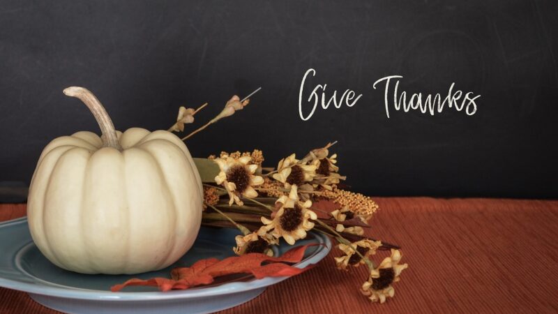 White pumpkin and yellow flowers on a platter with the words 