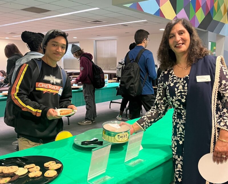 Faculty member Reena Goel offers cookies to student at the International Coffee Hour