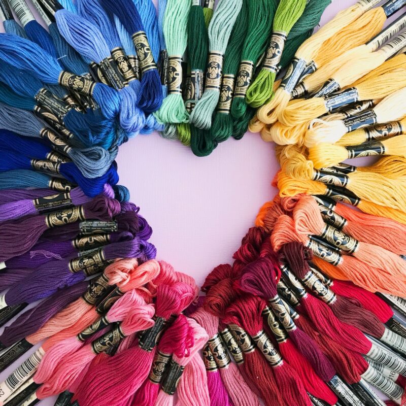 multi-colored skeins of yarn arranged in a circle, with a heart shape at the center