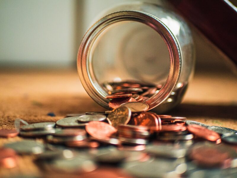 close-up photo of assorted coins spilling out of a coin jar