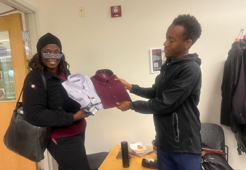 Two students holding two folded men's shirts