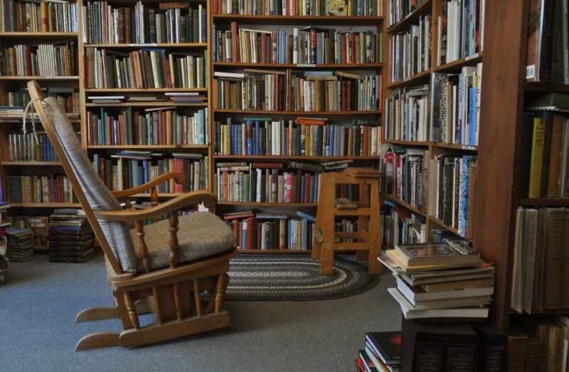 wooden rocking chair in front of wooden bookcases filled with books