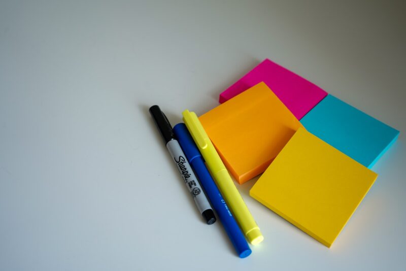 blue, black, and yellow pens beside orange, yellow, pink, and blue sticky notes