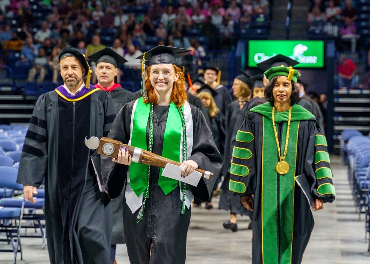The platform party enters the arena, led by Provost Robbin Hoopes, Student Speaker and College Mace Bearer Caitlin Lowe, and President Monica Posey
