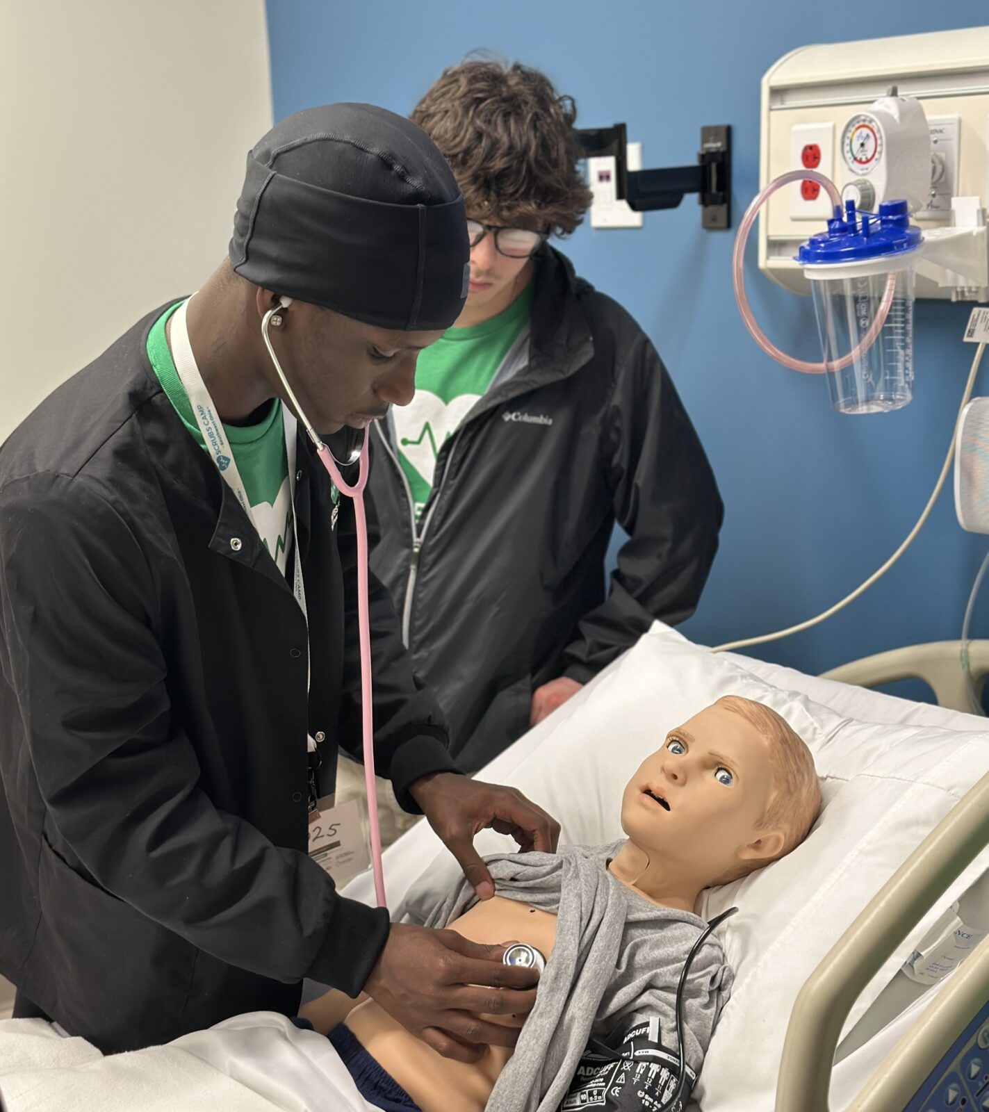 Students examine a child patient at Scrubs Camp 2025