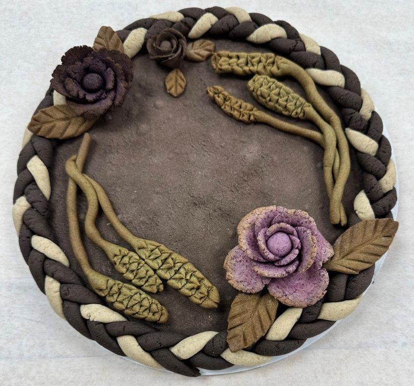 "Dead dough" sculpture - purple & black flowers, green stalks of wheat, black & white braided border