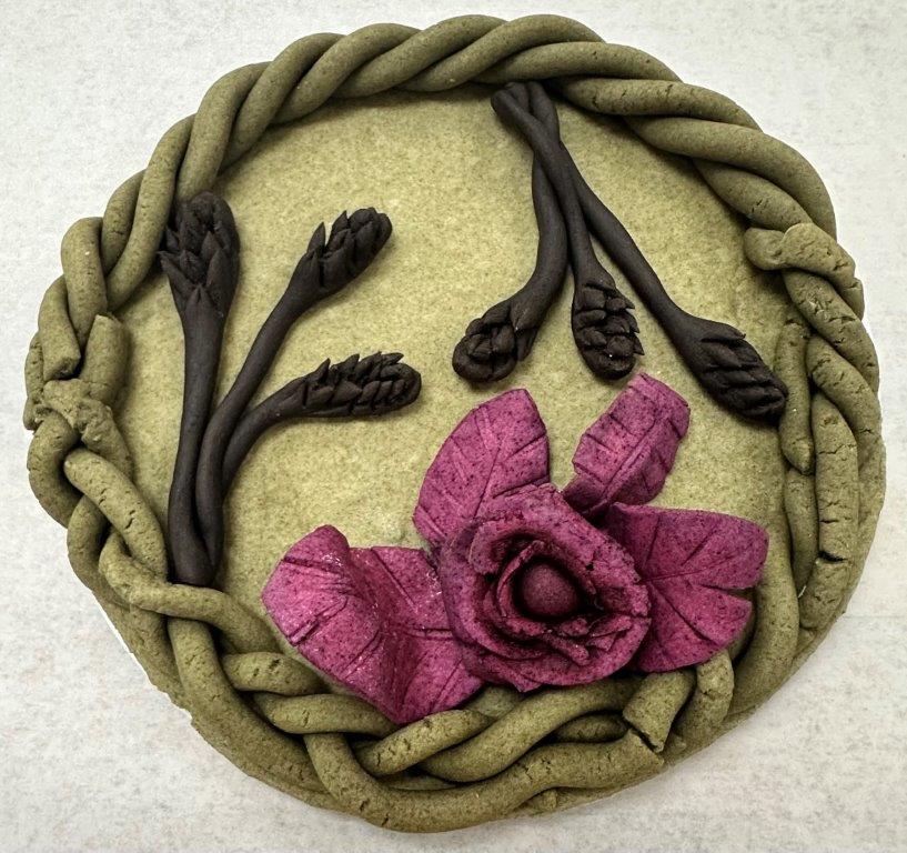 "Dead dough" sculpture - purple flowers, black stalks of wheat, green braided border