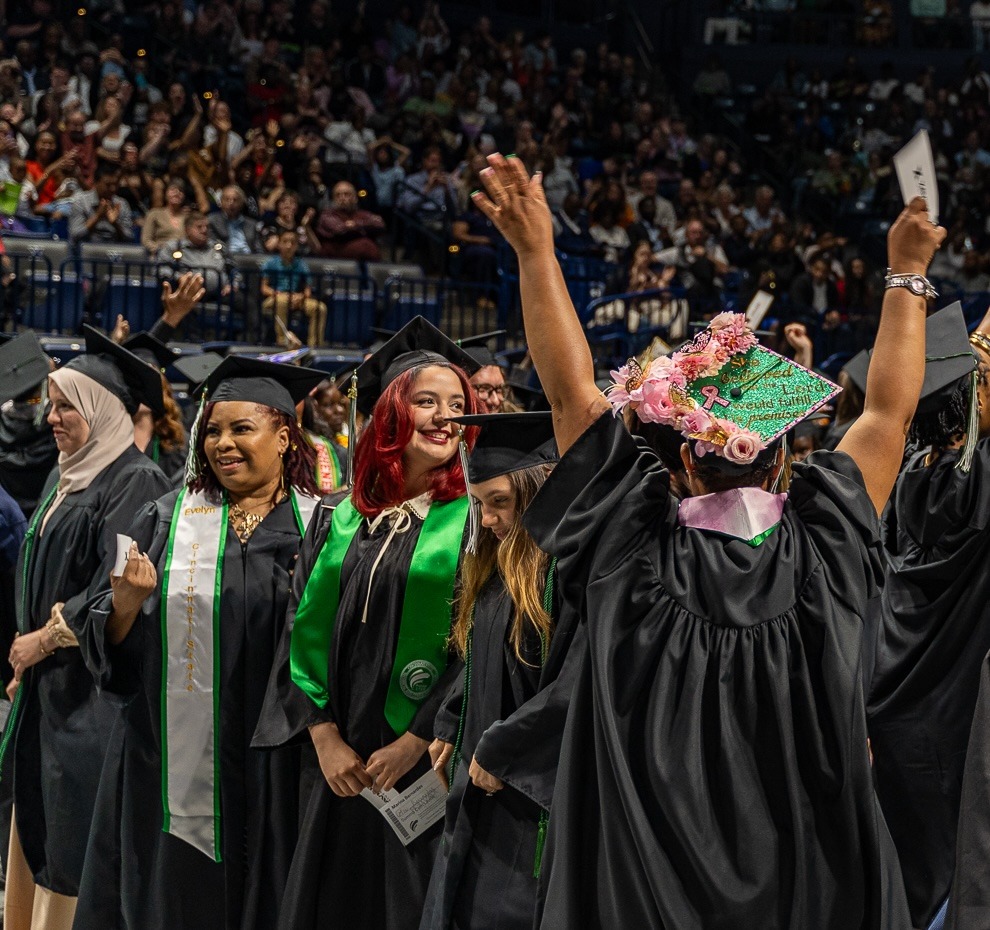 Graduates in a line, one with arms raised to the sky