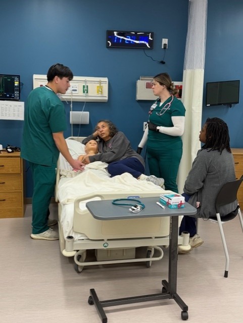 Nursing students handing the emergency with Nursing alumni representing "mom" and "doctor" nearby